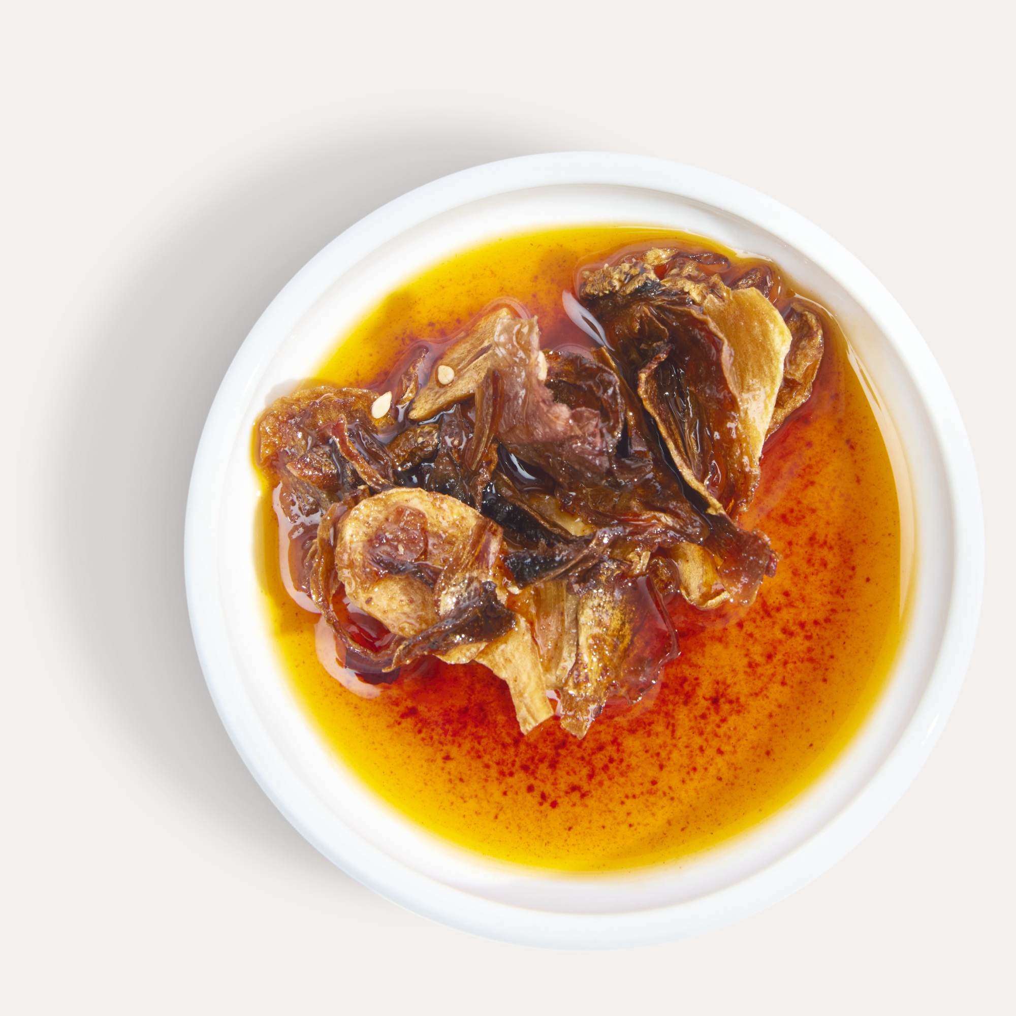 Vibrant, silky smooth Hot Girl Crunch Chili Oil with crispy chili crunches in a saucer - Hotgirlsauce chili oil - chili sauce - hot sauce