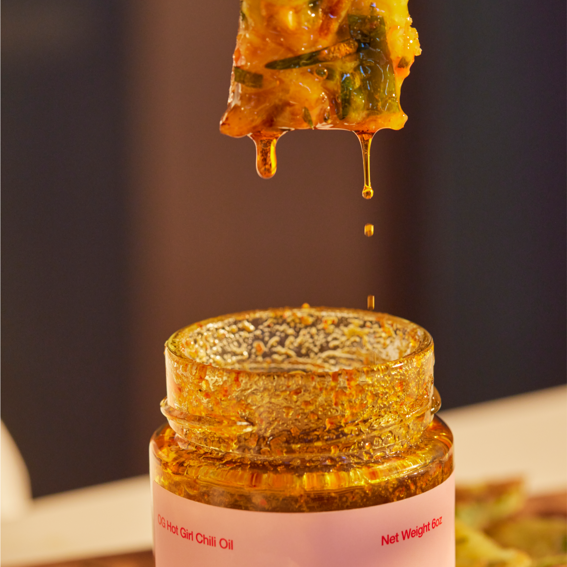 Food dripping into hot girl sauce chili oil jar